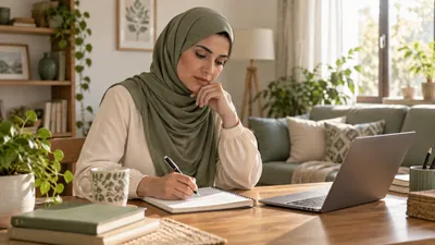 امرأة محجبة تراجع أسئلتها الصحية في دفتر بجوار حاسوب داخل غرفة منزلية مضاءة بهدوء